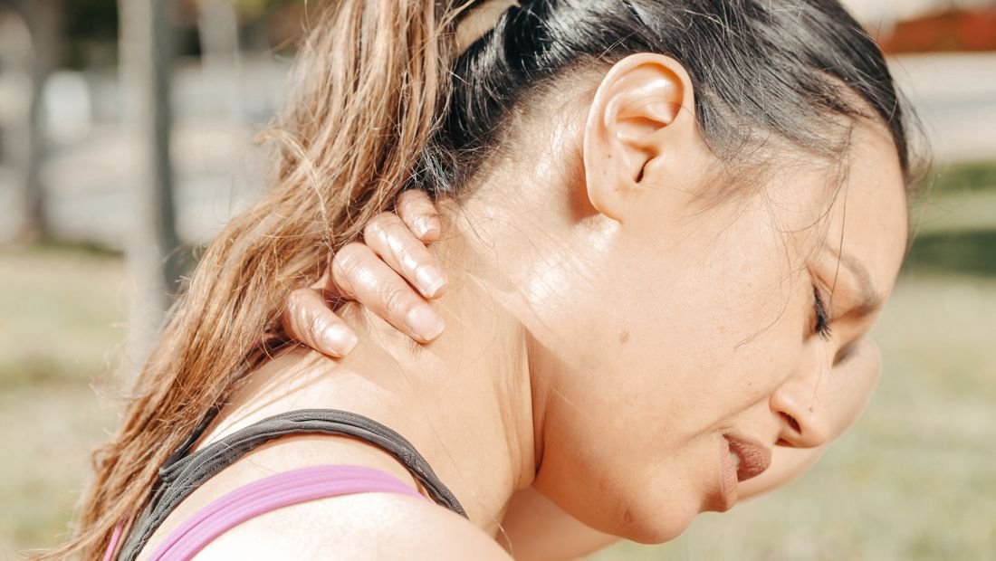 Woman holding the back of her neck and head in pain